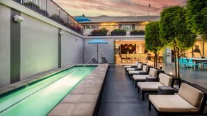 An outdoor pool area with lounge seating and a covered patio. - Hotel Lucent (Menlo Park)