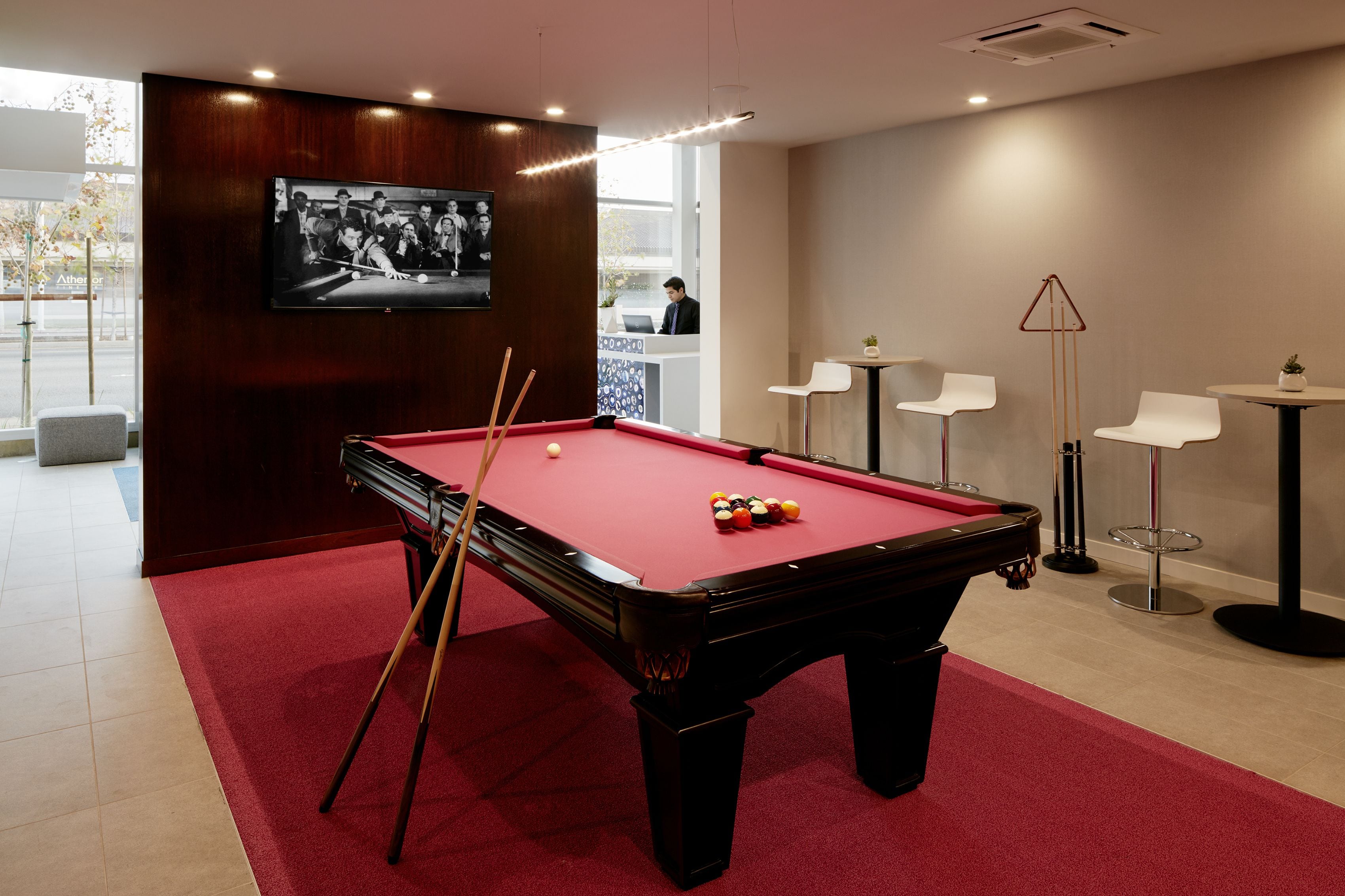 A pool table with balls, a television, and a bar area with chairs and a small table.