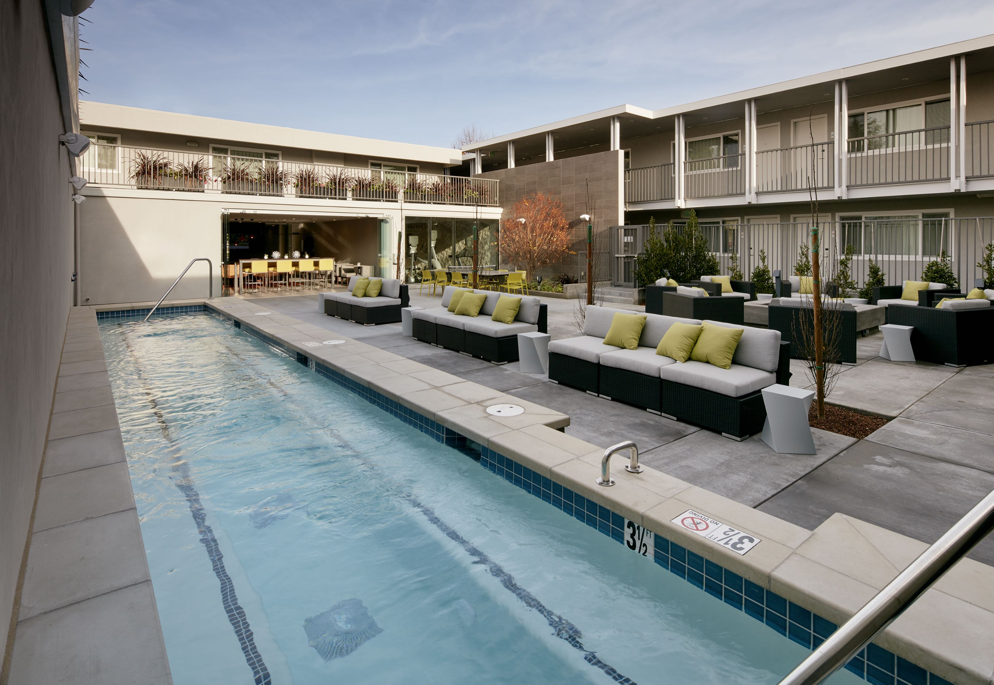 A pool area with a seating arrangement and a building with balconies.