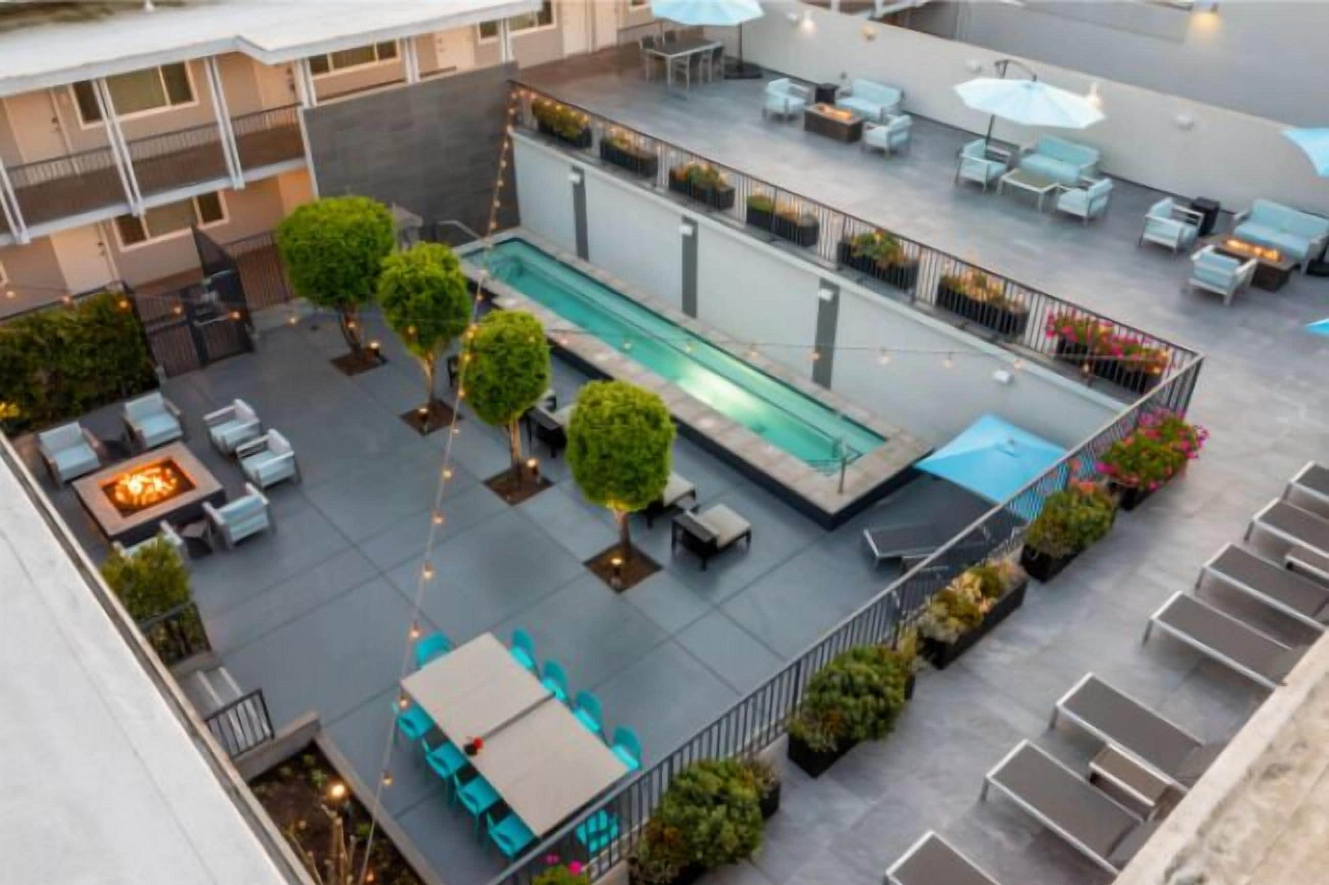 A rooftop patio with a pool, seating areas, and potted plants.