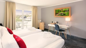 Une chambre d’hôtel avec deux lits, un bureau, une chaise, une lampe et une fenêtre avec des rideaux.