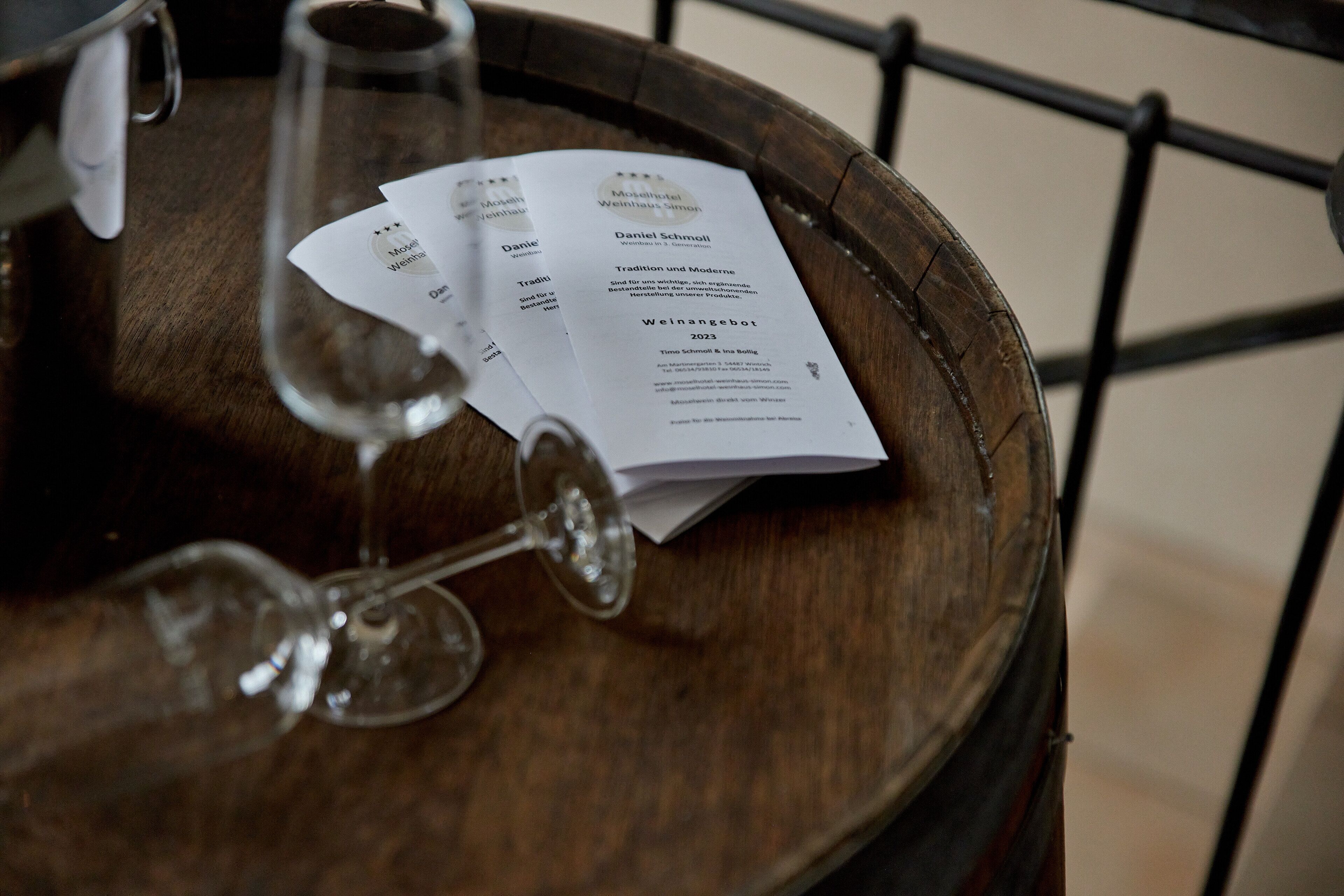 Un barril de madera con un menú y dos copas de vino sobre una mesa.