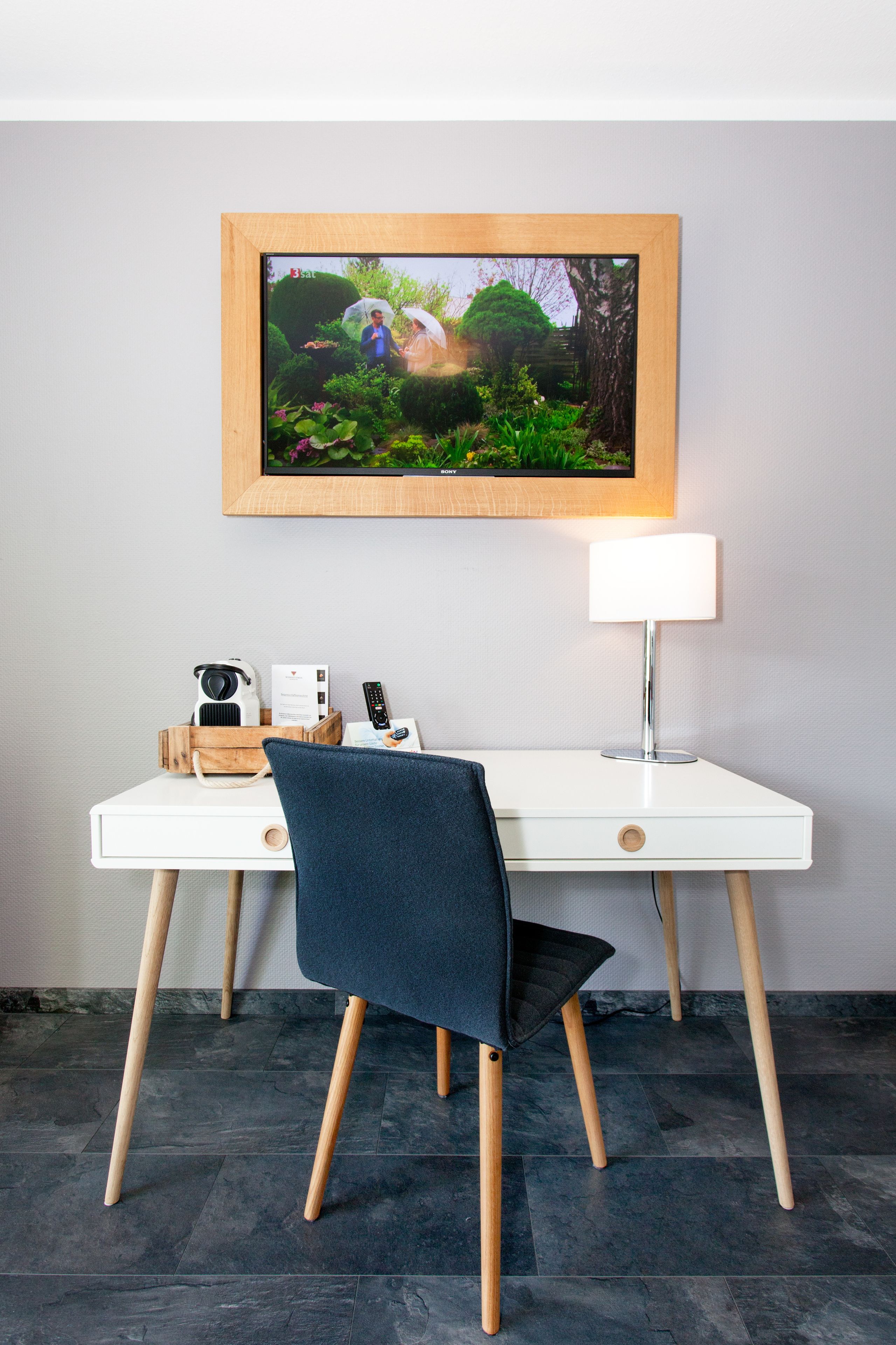 A modern office desk with a framed picture, a lamp, and a chair.