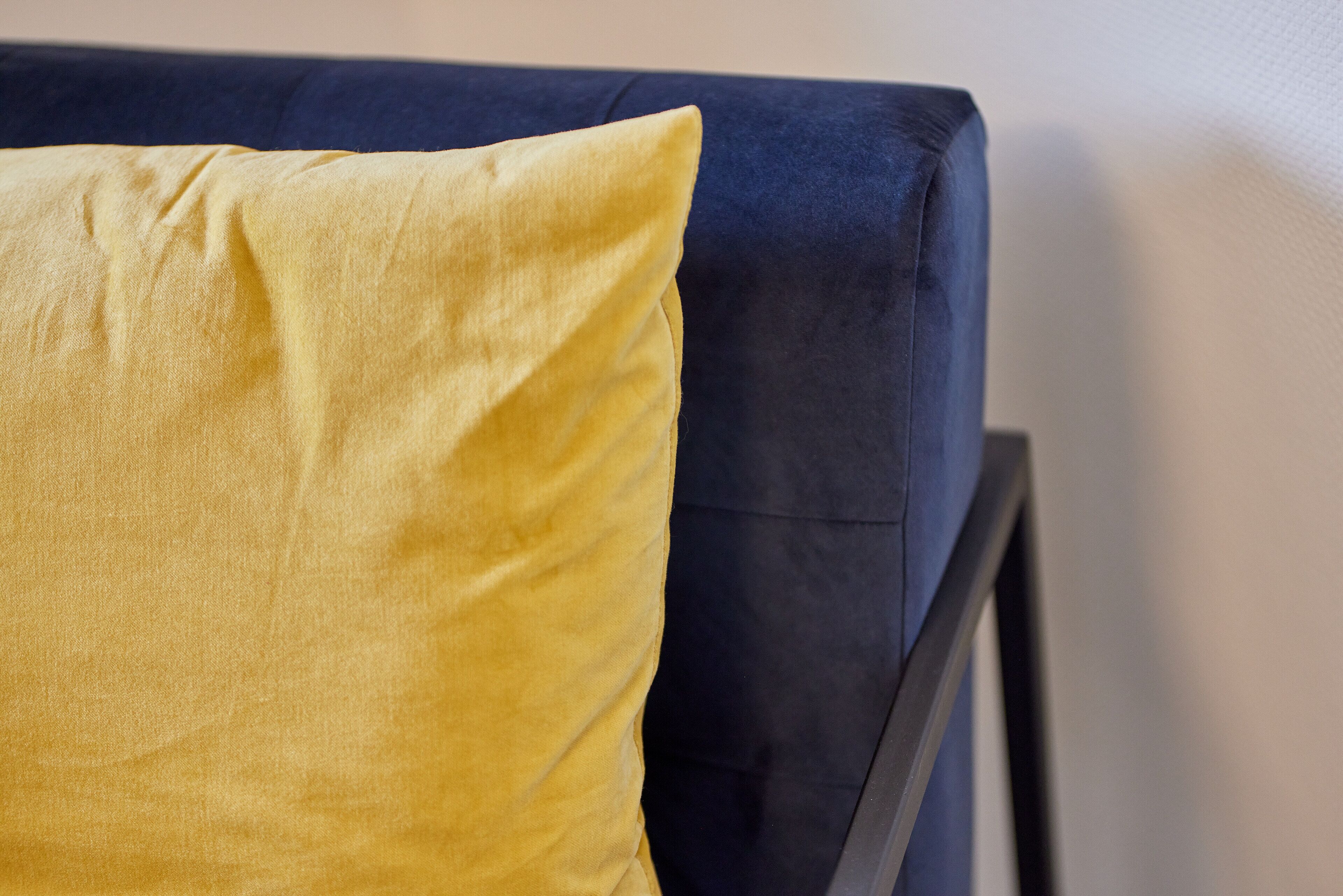 Un primo piano di un divano blu con un cuscino giallo.