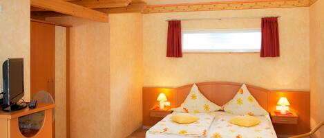 A bedroom with a wooden bed, bedside lamps, a television, and a wardrobe.
