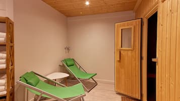 Ein Zimmer mit zwei grünen Lounge-Stühlen, einem kleinen Tisch und einer Holztür.