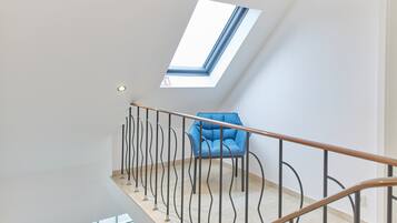Un interior moderno con una escalera, un sillón azul y un tragaluz.