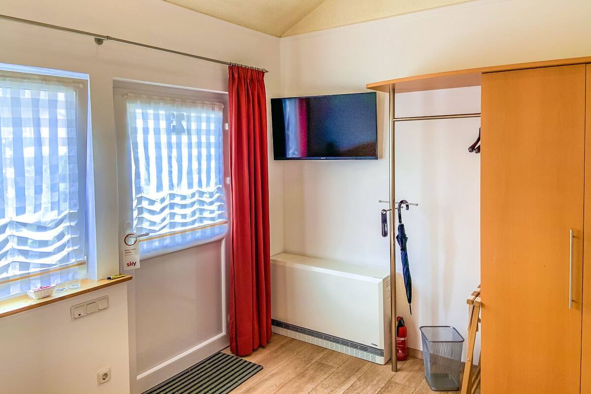 Une chambre dotée d’une douche, de toilettes, d’un lavabo, d’un téléviseur fixé au mur et d’une armoire en bois.