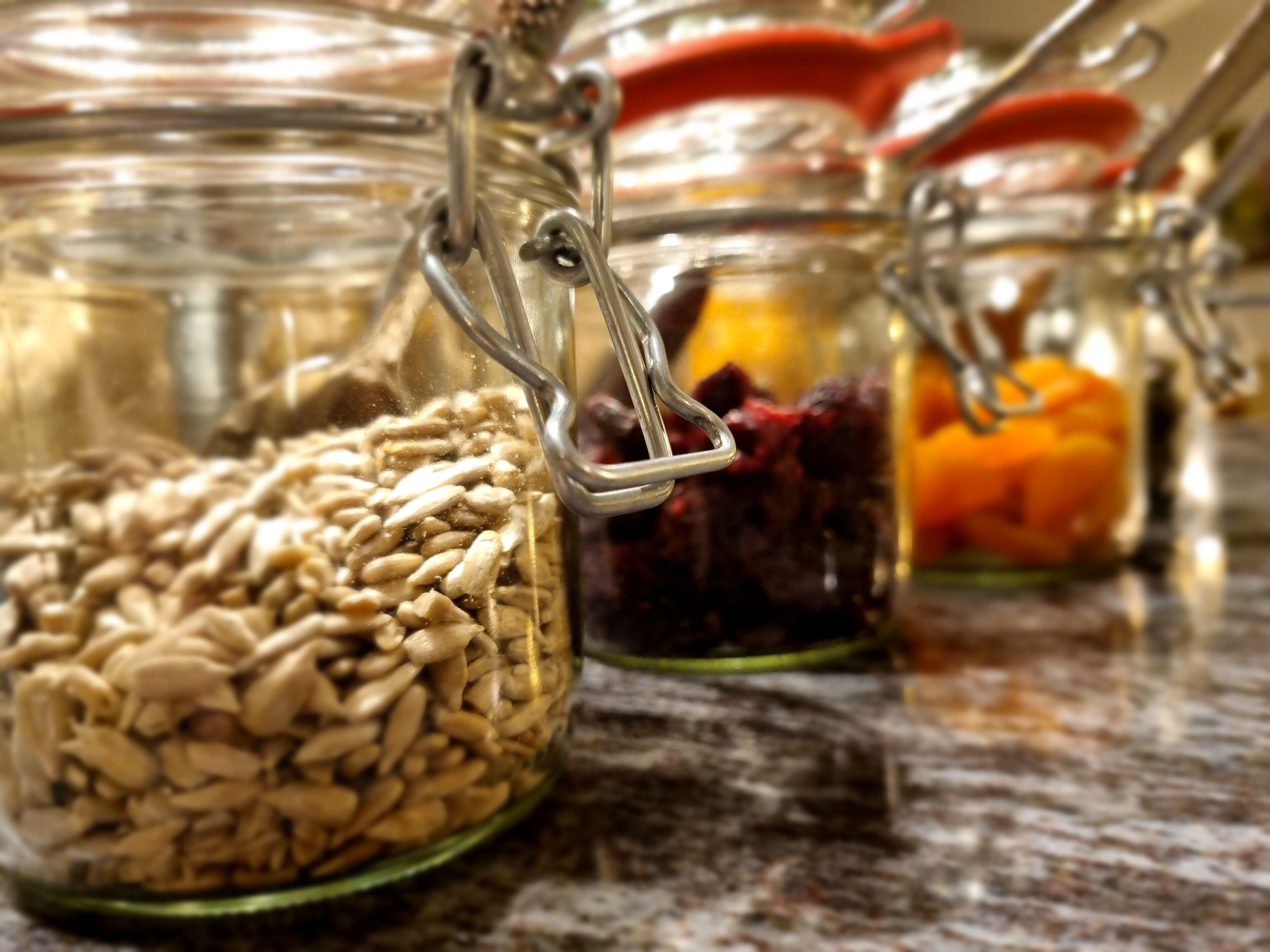 Three glass jars with metal clasps containing different food items.