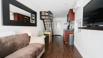 Un espace de vie compact comprenant un canapé, un coin repas, une cuisine et un escalier.