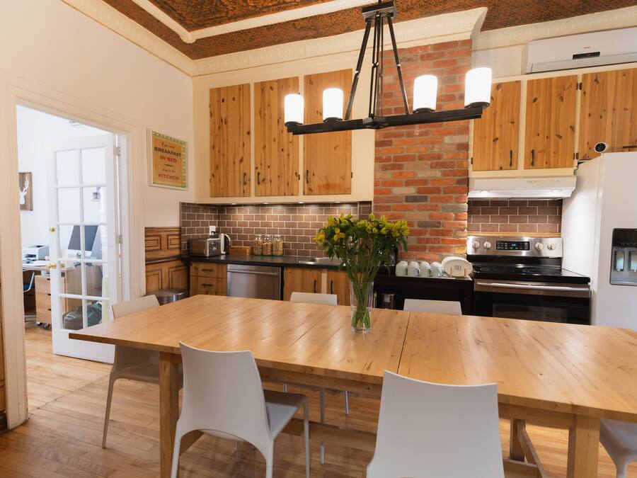 A modern kitchen with wooden cabinets, a brick accent wall, and a central island with chairs.