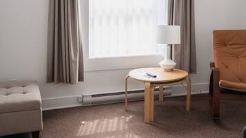 Habitación de hotel con un ventanal grande, una mesa redonda con lámpara, un sofá y una silla.