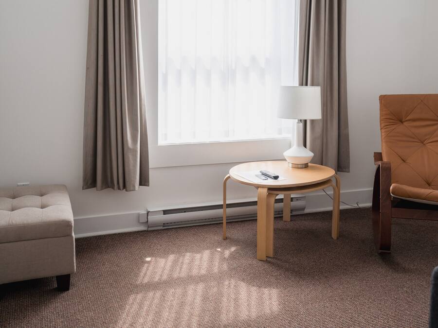 Habitación de hotel con un ventanal grande, una mesa redonda con lámpara, un sofá y una silla.