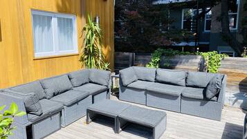 A wooden deck with two grey sectional sofas and a matching ottoman.