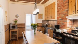 Una cocina moderna con armarios de madera, pared de ladrillo y una amplia mesa de comedor con sillas blancas.