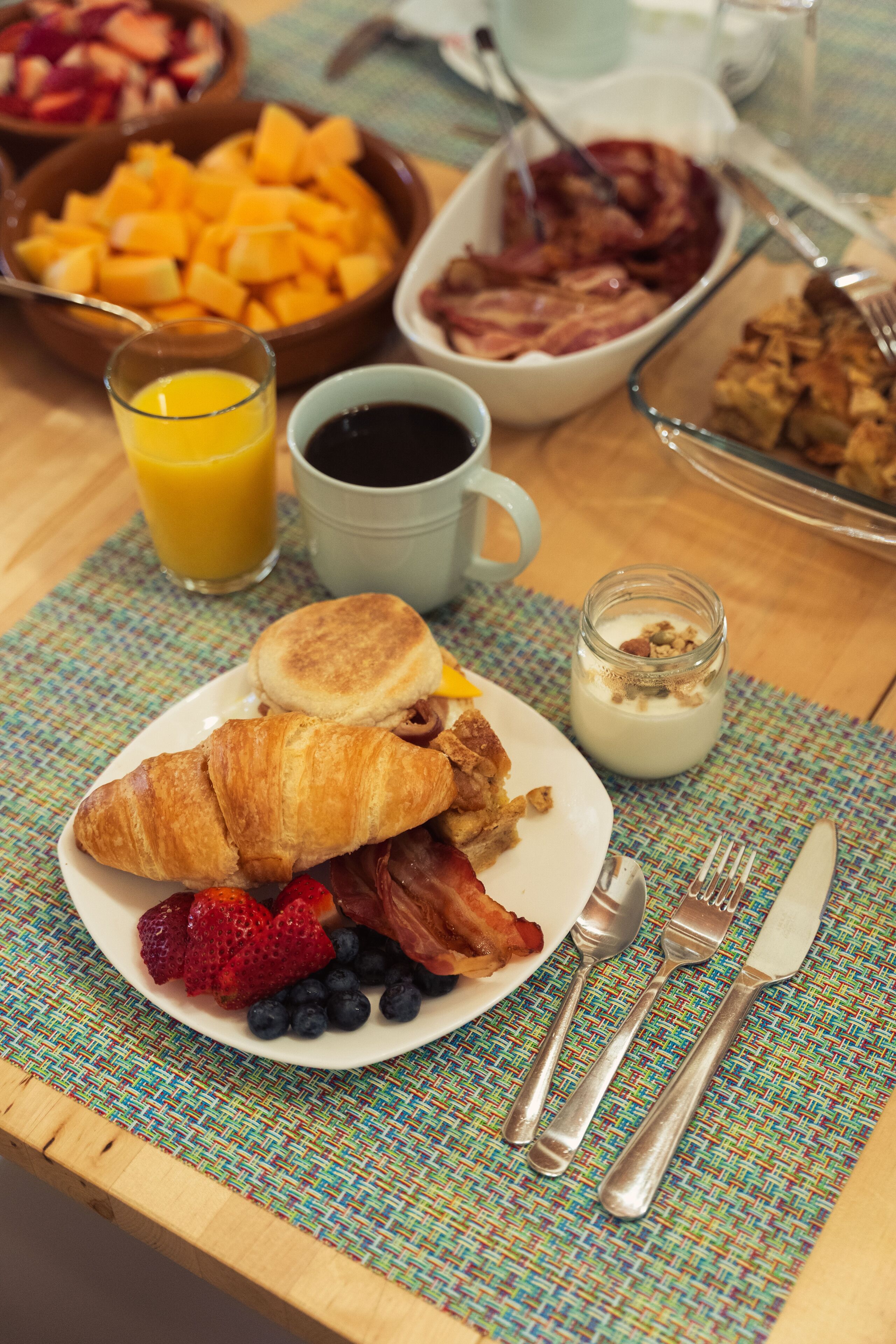 Une assiette de petit-déjeuner avec des croissants, des fraises, des myrtilles et du bacon.