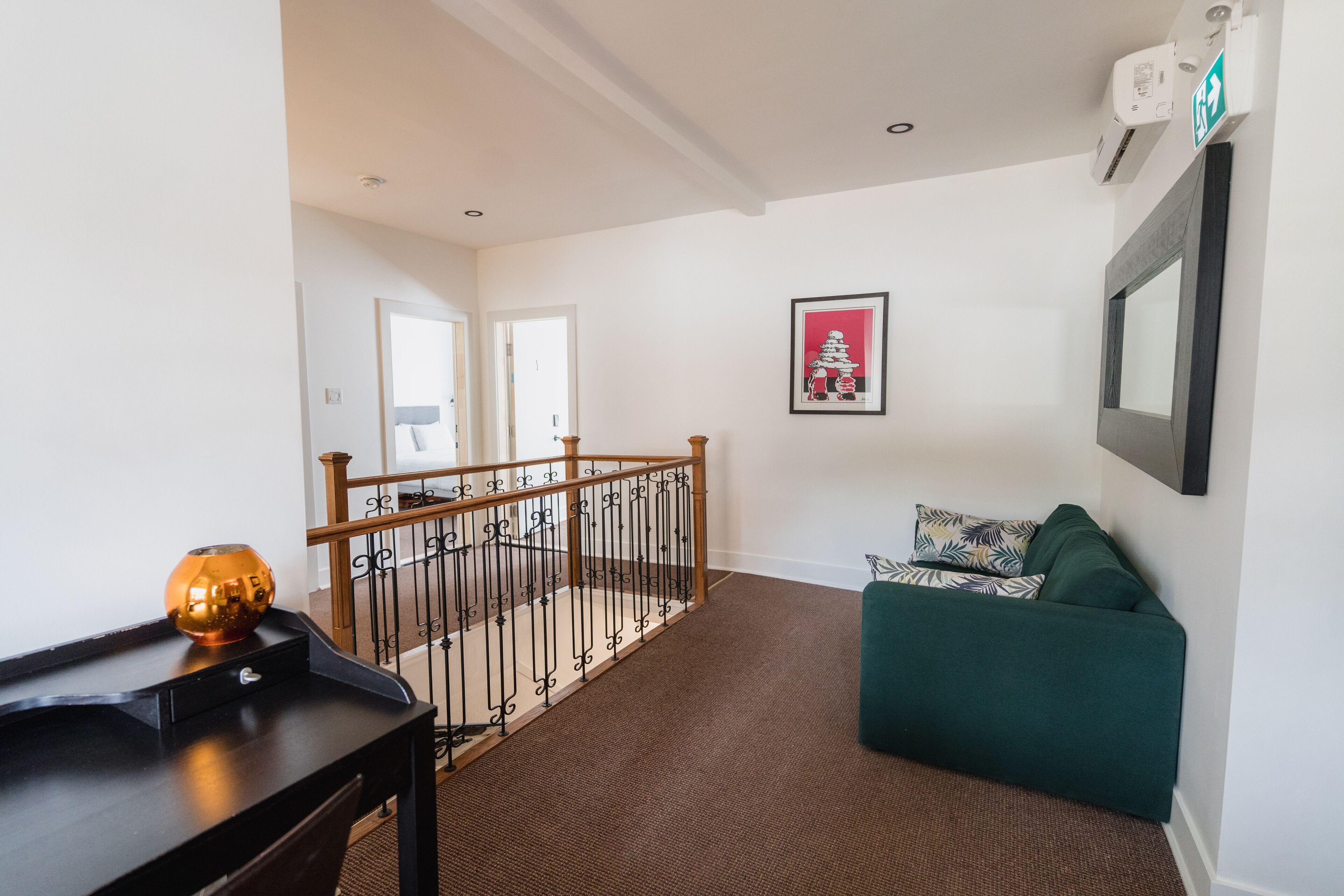 A hallway with a staircase, a green sofa, and a framed picture on the wall.