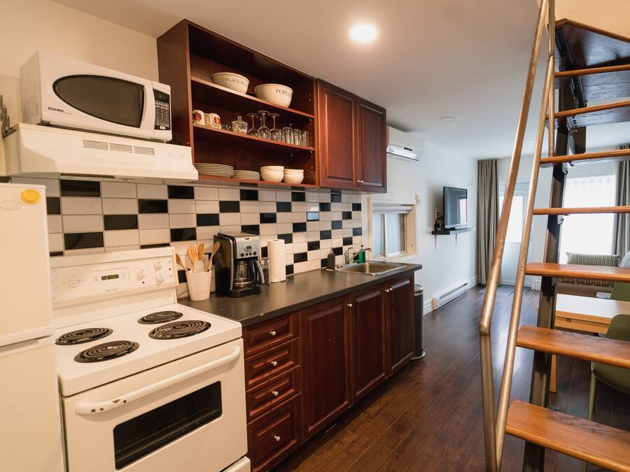 A compact kitchen with a microwave, stove, and checkered backsplash.