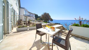A patio with a table set for breakfast, overlooking a coastal view.
