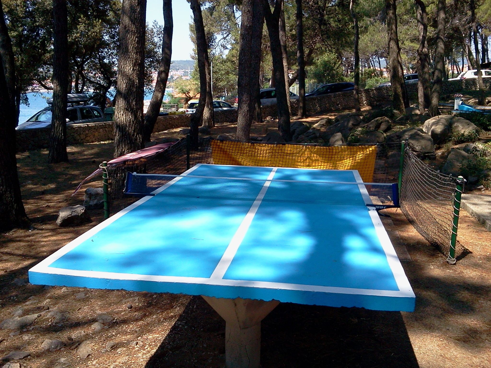 Un court de tennis entouré d’arbres et de rochers.