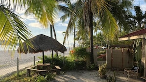 A beachside patio with a thatched umbrella, seating, and potted plants. - Mali-Mali Beach Resort (Langkawi)