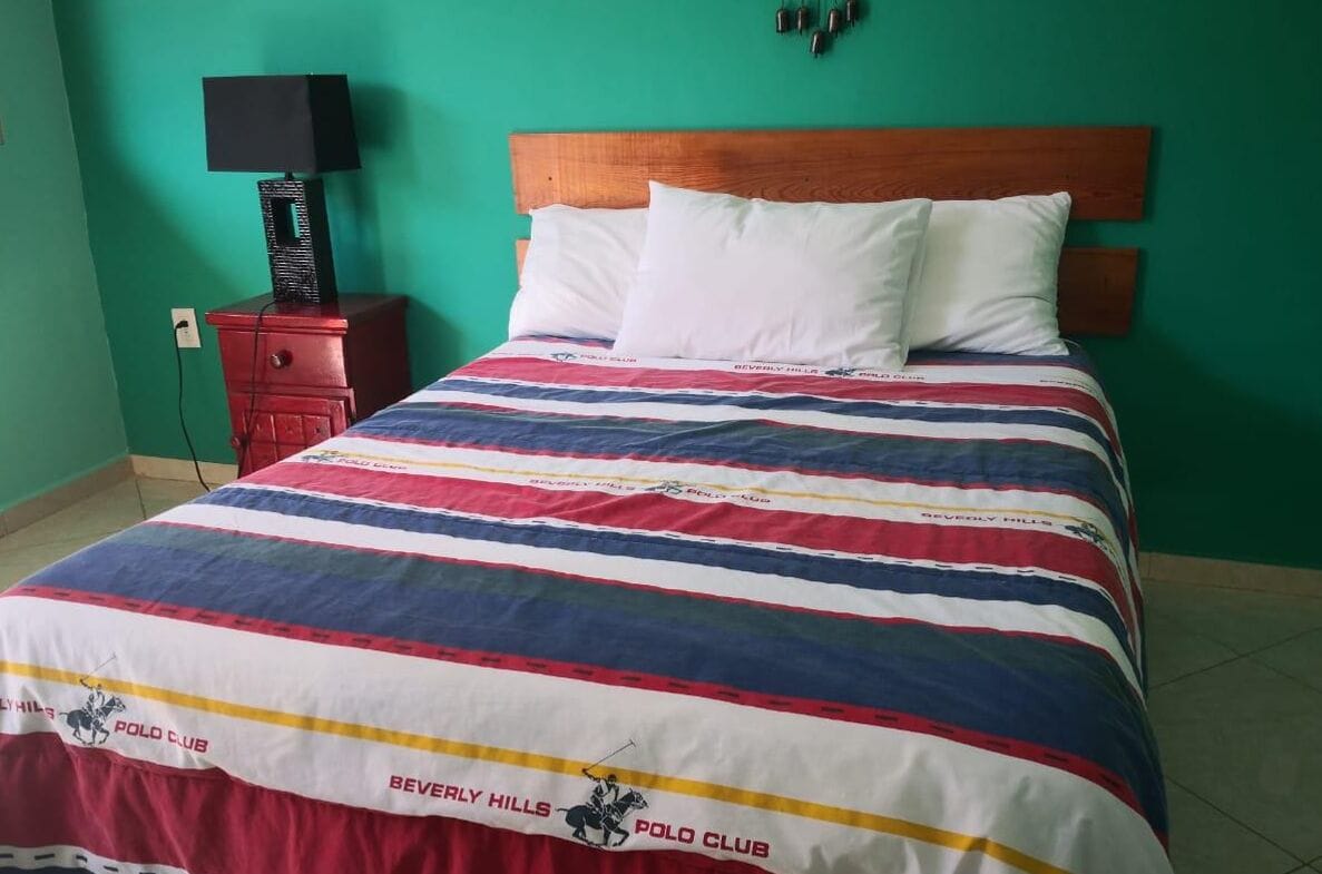 Ein Hotelzimmer mit einem Bett, einem Nachttisch mit Lampe und einer grünen Wand.