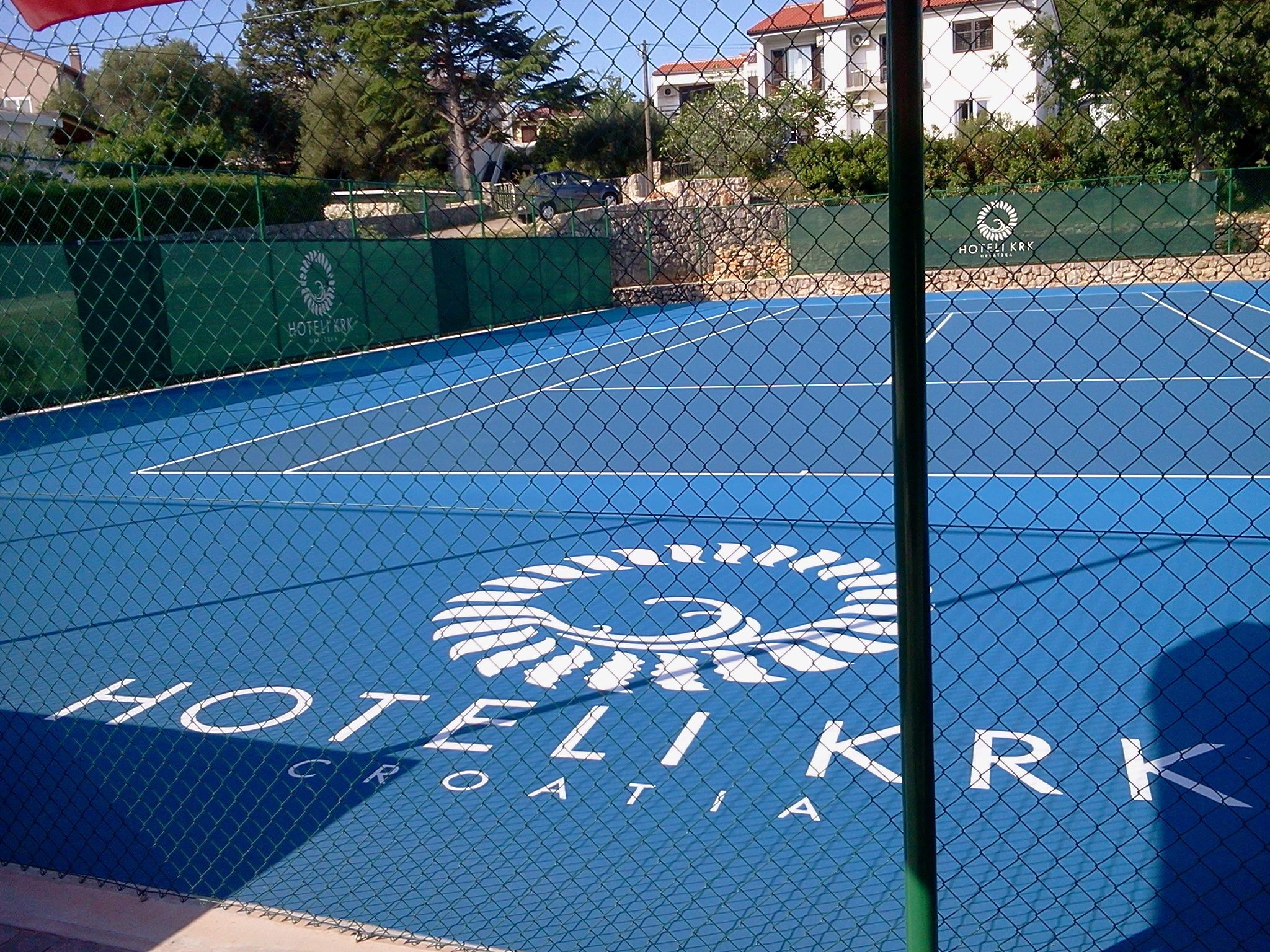Una cancha de tenis azul con el logotipo y el nombre del Hotel KRIK en Croacia.