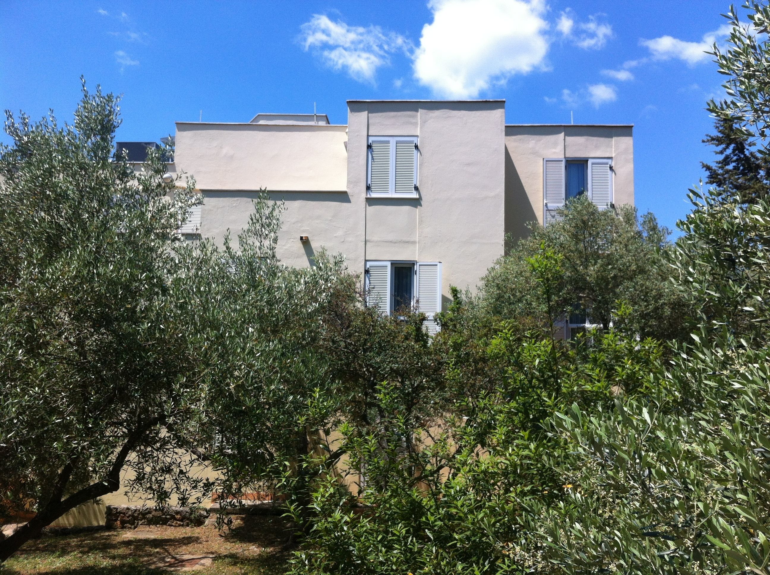 Un bâtiment moderne doté d’un toit plat, de murs blancs et de volets aux fenêtres.