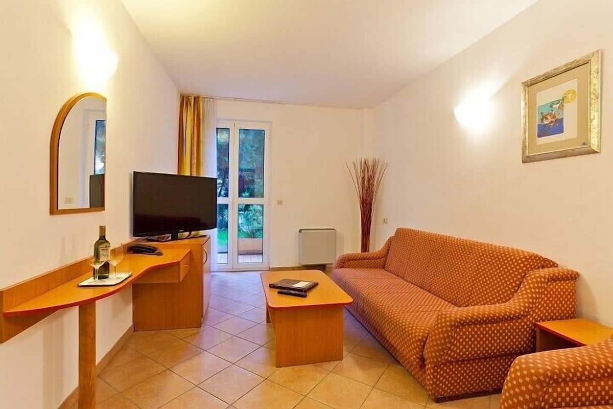 A living room with a sofa, a TV, a wooden desk, and a chair.