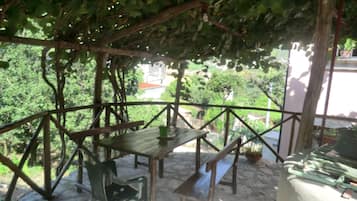 Relax in a serene garden setting with a patio, complete with a wooden table and chairs.
