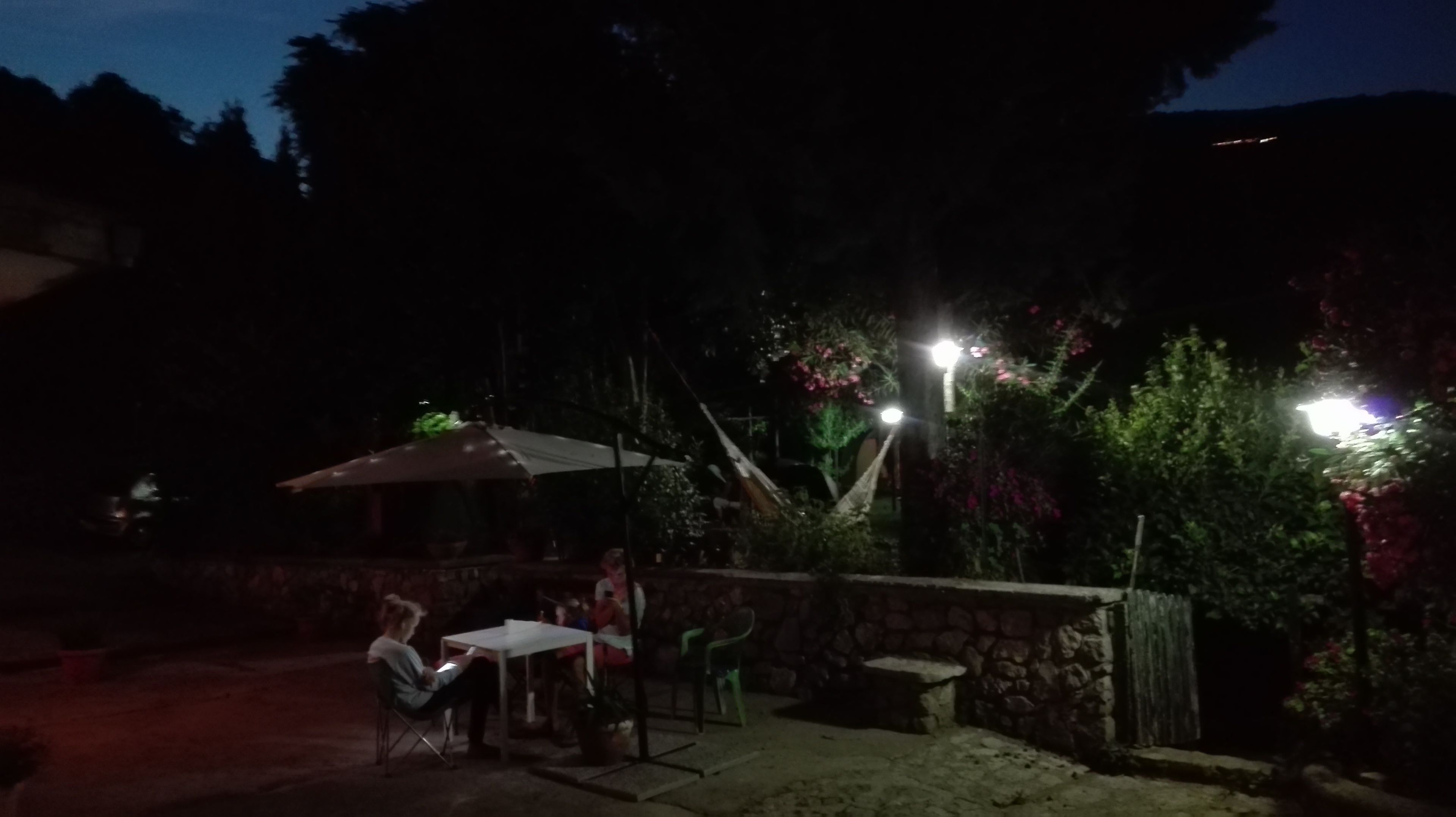 An outdoor patio area with a table and chairs, a covered seating area, and a stone wall.