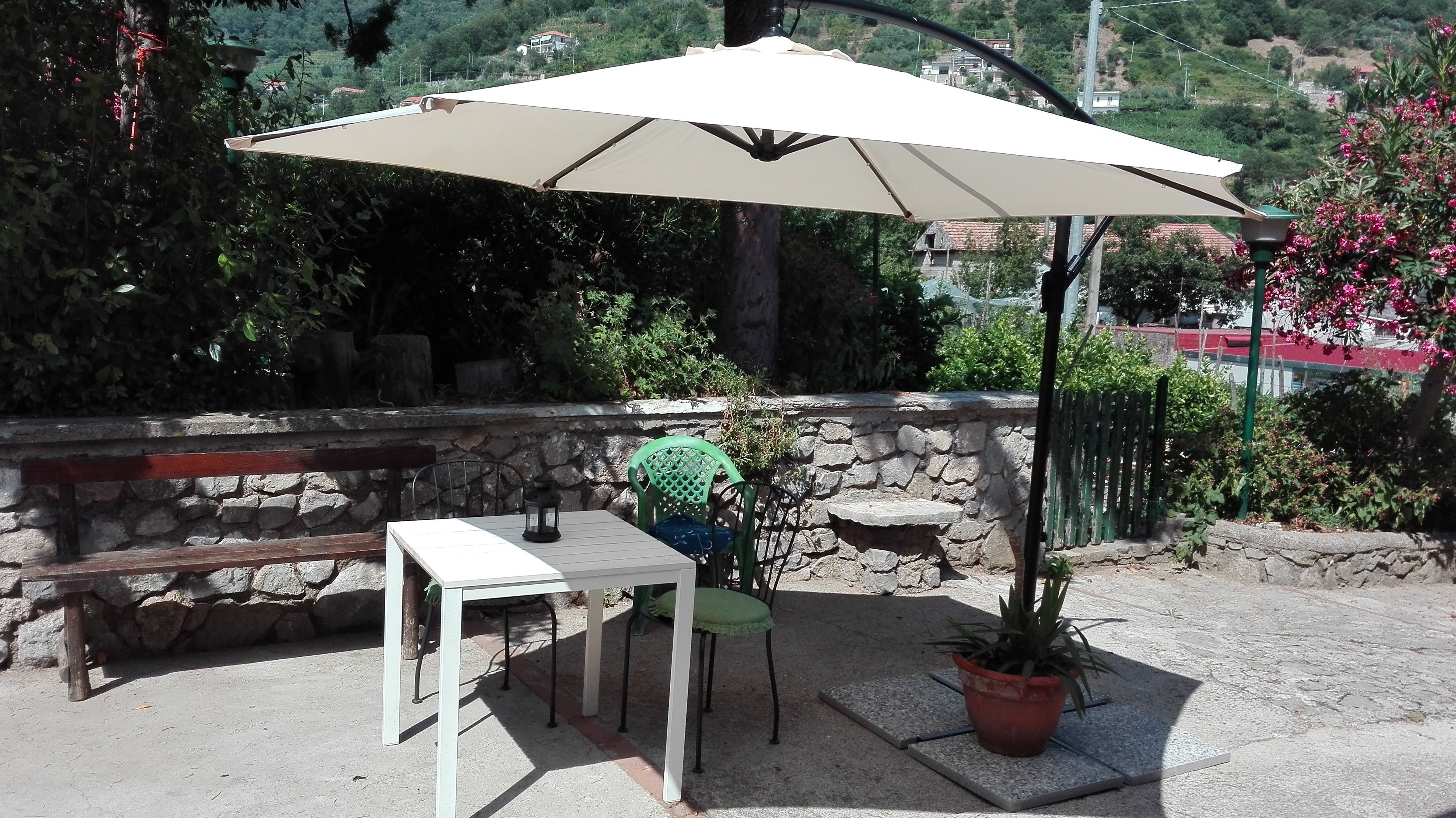An outdoor patio with a table and chairs, a potted plant, and a stone wall.