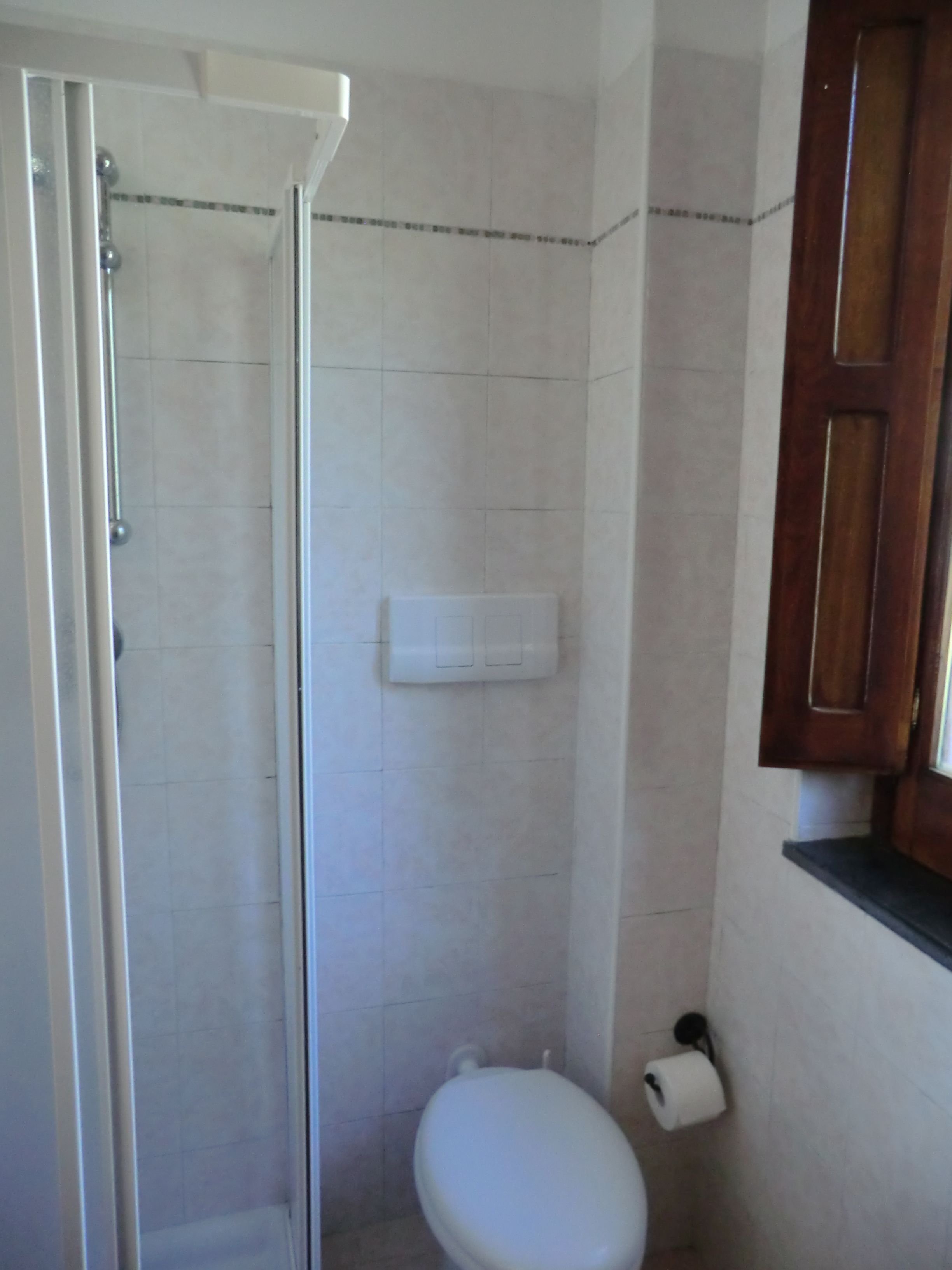 Un baño con ducha, inodoro y dispensador de toallas de papel.