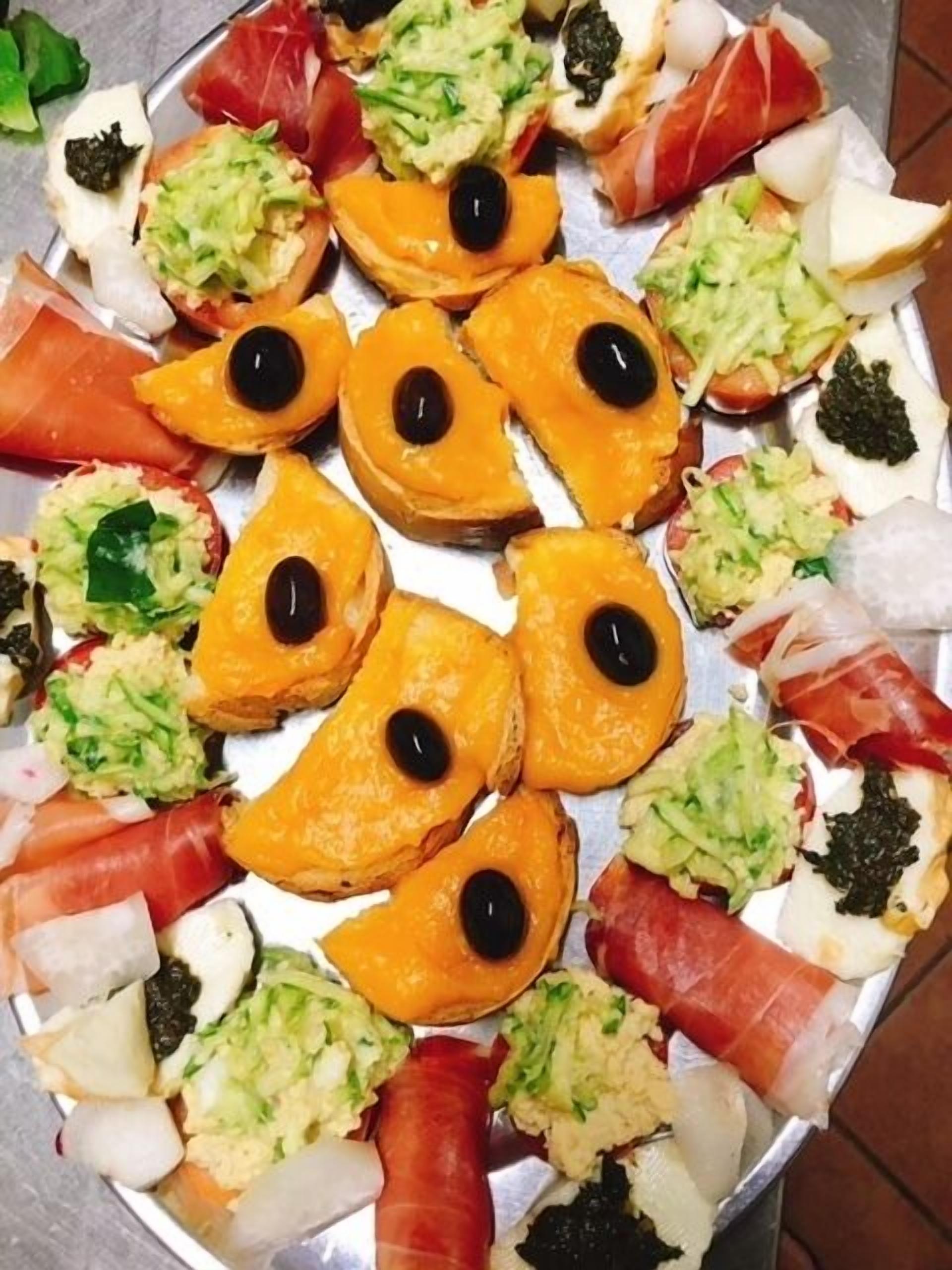 A tray of assorted appetizers including slices of orange, olives, and various garnishes.
