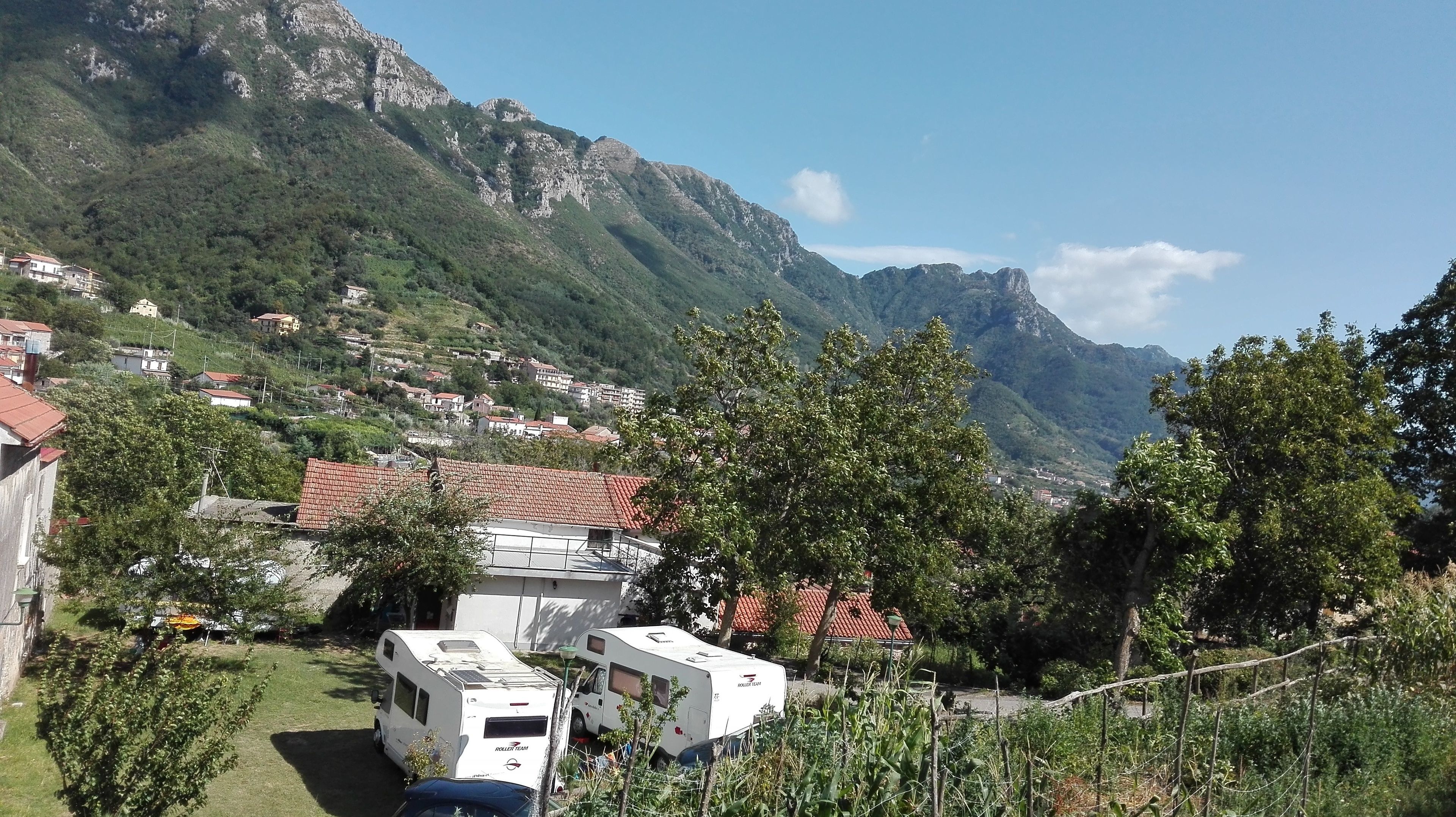 A camper parked in a grassy area with a mountainous backdrop.
