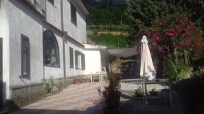 Ein weißes Gebäude mit einer gefliesten Terrasse, Außenbestuhlung und Blumentöpfen.