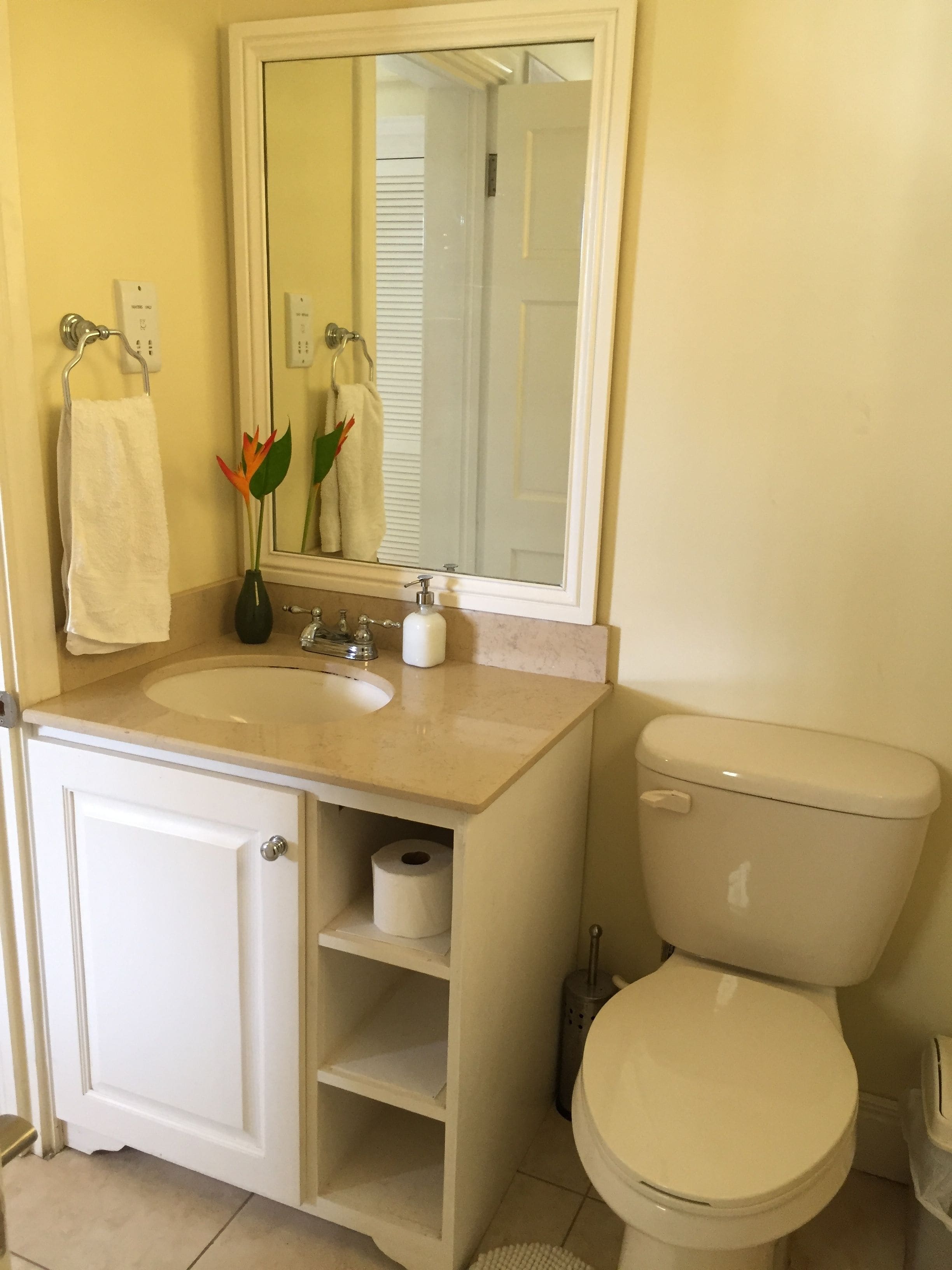 A bathroom with a white sink, mirror, toilet, and a towel rack.