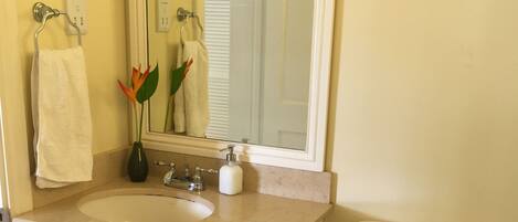 A bathroom with a white sink, mirror, toilet, and a towel rack.
