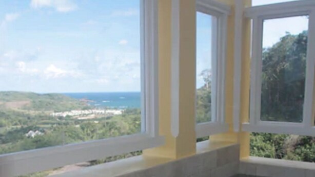 A swimming pool with a view of a landscape and distant buildings. - South Sea House (Gros Islet)