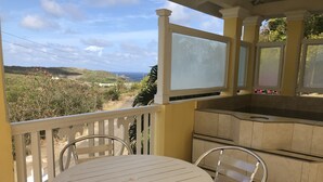 A balcony with a white table and chairs, a kitchen area, and a view of the landscape. - South Sea House (Gros Islet)