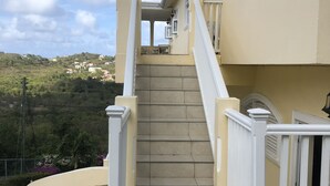A beige house with a white staircase leading to a balcony. - South Sea House (Gros Islet)