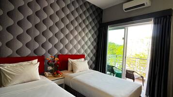 A modern hotel room with two beds, a red headboard, a patterned wall, an air conditioning unit, and a balcony with a view.