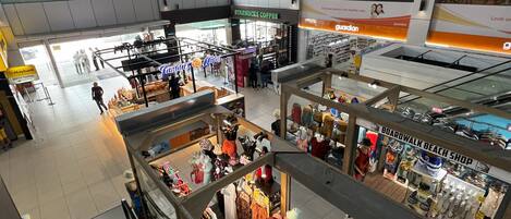 An indoor shopping mall with multiple stores, including a boardwalk beach shop and a Starbucks.