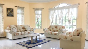 Una sala de estar con dos sofás, una mesa de centro y un ventanal con cortinas.