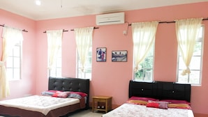 Una habitación con dos camas, paredes rosas y una pequeña mesita de noche de madera.