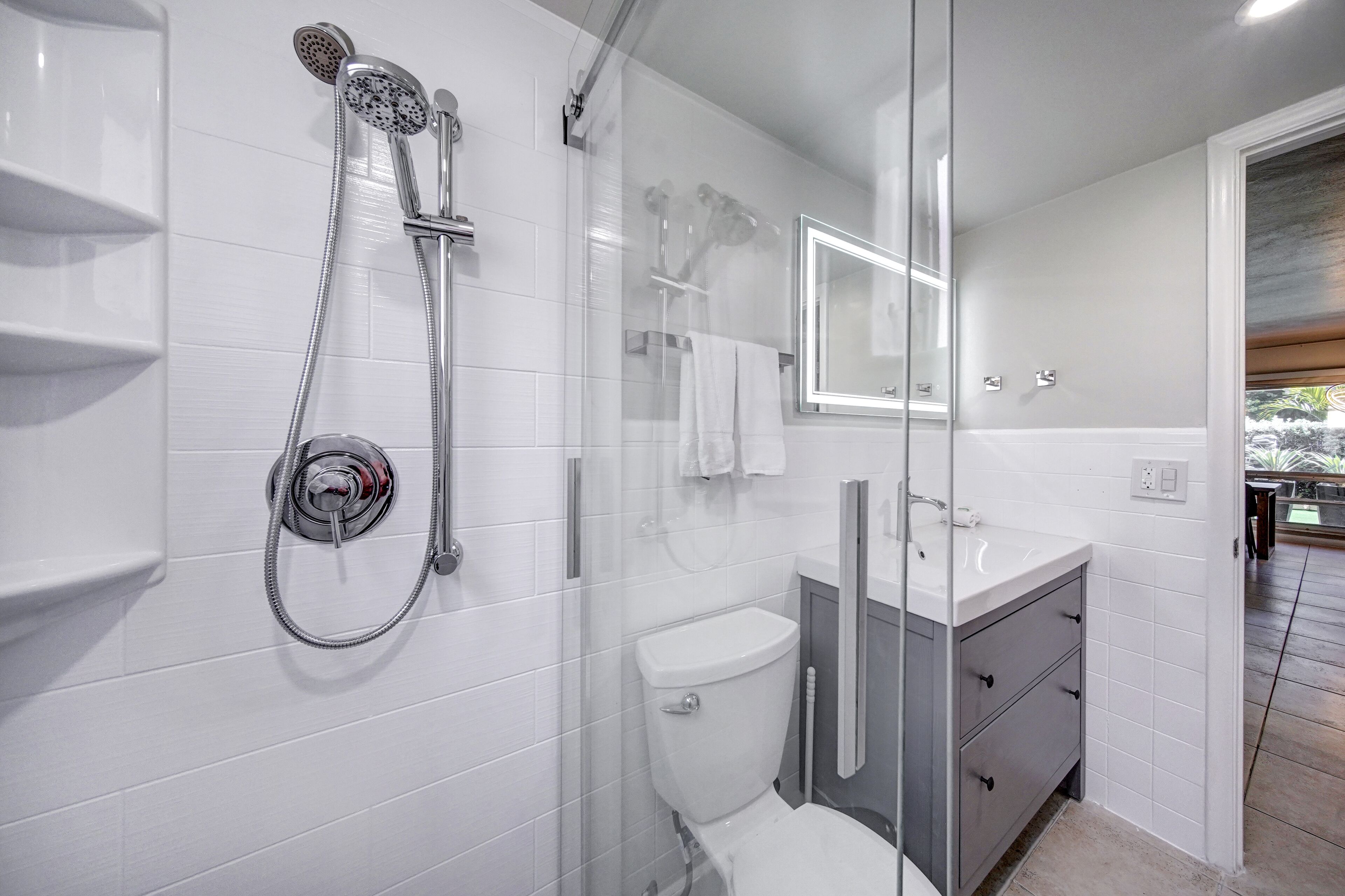 Une salle de bain moderne avec une douche à parois de verre, des toilettes et un meuble-lavabo avec un miroir.
