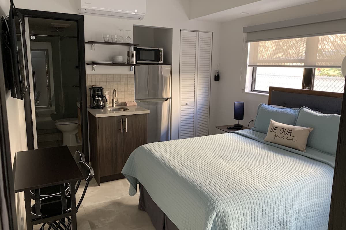 Een kleine slaapkamer met een bed, nachtkastje en een raam met uitzicht.