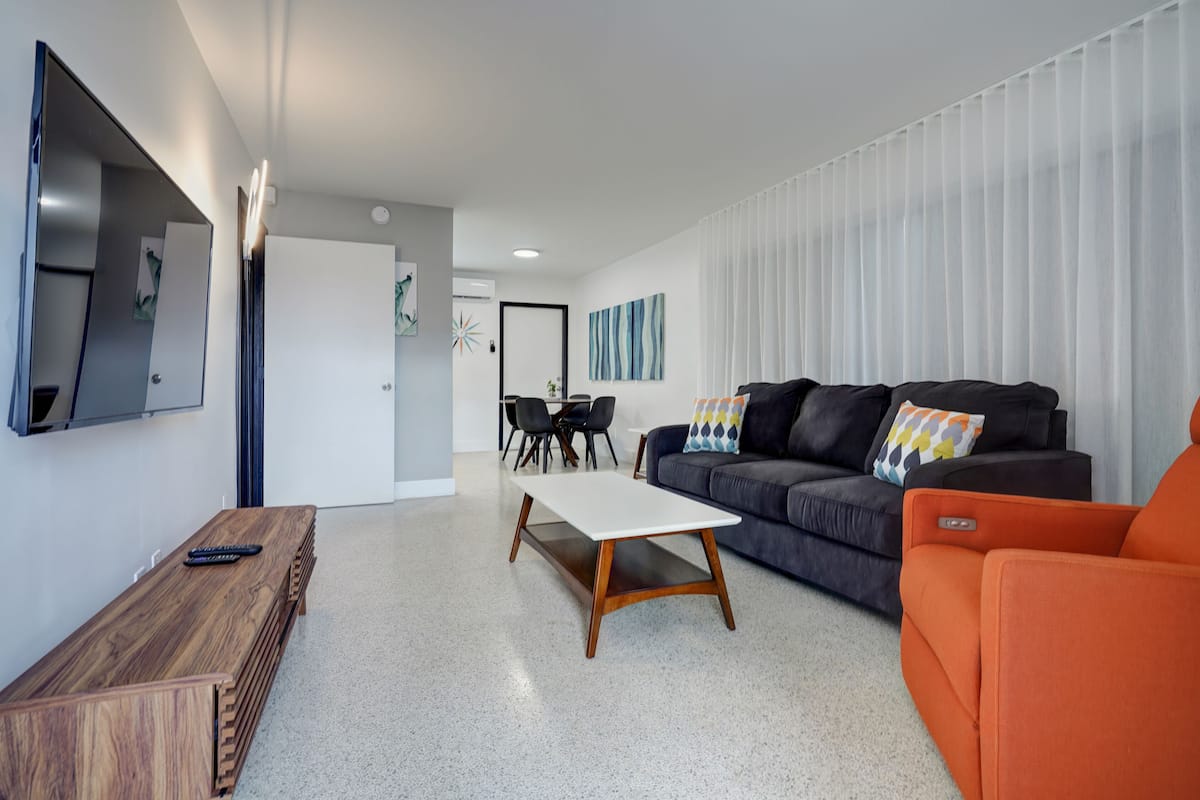 Een moderne woonkamer met een bank, een salontafel en een aan de muur bevestigde televisie.