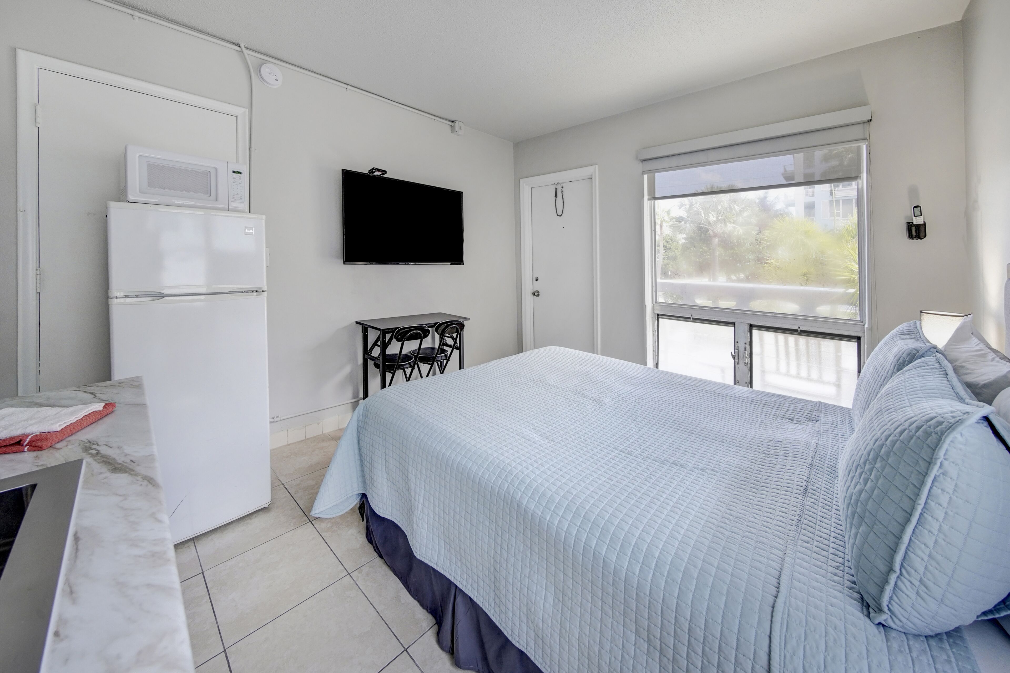 Un dormitorio con una cama, televisión, microondas y refrigerador.