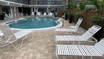 A pool area with lounge chairs and a pool.